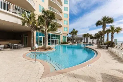 a swimming pool in front of a building with palm trees at Aqua 2102 in Panama City Beach