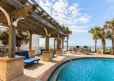 a swimming pool with a pergola and the ocean at Aqua 2102 in Panama City Beach