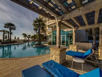 a swimming pool with blue chairs and a building at Aqua 2102 in Panama City Beach
