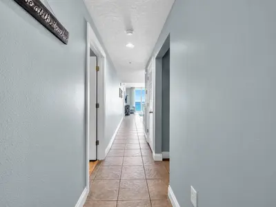 a hallway with white walls and a tile floor at Palazzo 1406 by Emerald Coast Retreats in Panama City Beach