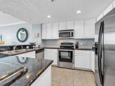 a kitchen with white cabinets and stainless steel appliances at Palazzo 1406 by Emerald Coast Retreats in Panama City Beach