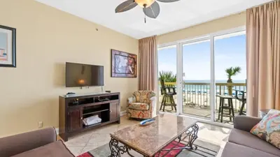 a living room with a couch and a television and a balcony at 204 West Calypso 2nd floor Gulf Front Specials! in Panama City Beach