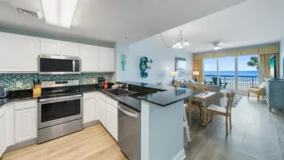 a kitchen with white cabinets and a view of the ocean at Calypso 206W Low Floor West Tower No elevators needed in Panama City Beach