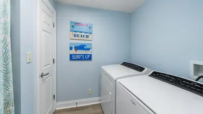 a laundry room with a washer and a sign on the wall at Calypso 206W Low Floor West Tower No elevators needed in Panama City Beach