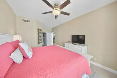 a bedroom with a pink bed and a ceiling fan at Calypso 208 East Direct Gulf Front Exceptional in Panama City Beach