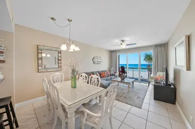 a dining room and living room with a table and chairs at Calypso 208 East Direct Gulf Front Exceptional in Panama City Beach