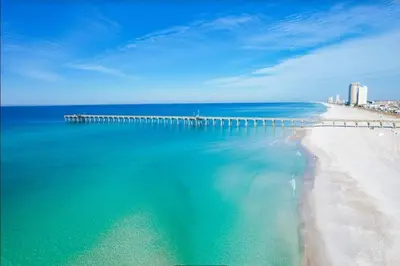 a view of a beach with a pier in the water at Calypso 209E 2nd floor Corner Unit 2 BR direct beach front in Panama City Beach