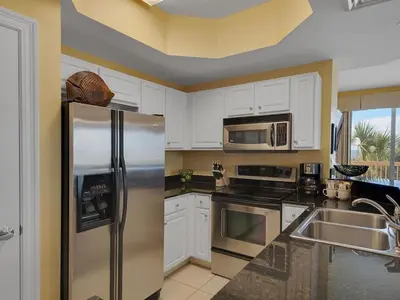 a kitchen with white cabinets and a stainless steel refrigerator at Calypso 209W Incredible Corner unit Best view in PCB in Panama City Beach