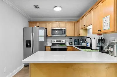 a kitchen with wooden cabinets and a stainless steel refrigerator at Spring Break! Heated Pool, Walk 2 Beach, Sleeps 11 in Panama City Beach