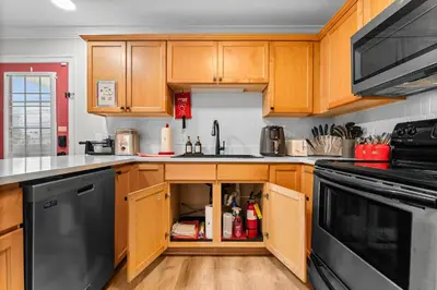 a kitchen with wooden cabinets and black appliances at Spring Break! 2 Homes, 2 Pools, Sleeps 22 in Panama City Beach