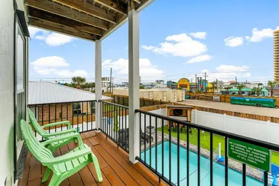 a balcony with two chairs and a swimming pool at Spring Break! 2 Homes, 2 Pools, Sleeps 22 in Panama City Beach