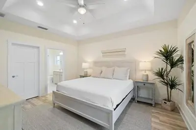 a white bedroom with a large bed and a table at Palm Paradise in Panama City Beach