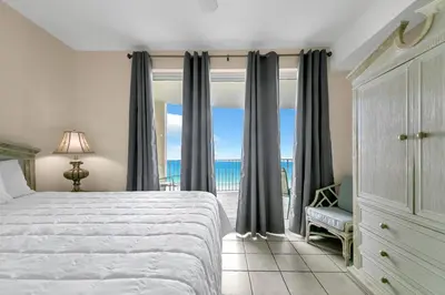 a bedroom with a bed and a view of the ocean at Twin Palms 702 in Panama City Beach