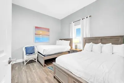 a bedroom with two beds and a chair in it at Sterling Breeze 205 in Panama City Beach