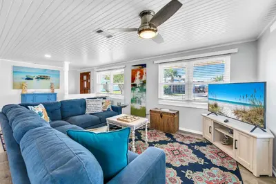 a living room with a blue couch and a flat screen tv at A Wave We Go in Panama City Beach