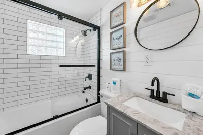 a white bathroom with a sink and a mirror at A Wave We Go in Panama City Beach