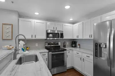 a kitchen with white cabinets and a stainless steel refrigerator at Calypso 302 West Direct Beach Front Awesome! in Panama City Beach