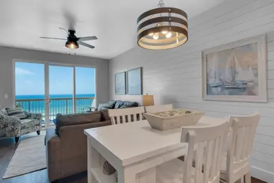 a living room with a table and a living room with a view at Calypso 302 West Direct Beach Front Awesome! in Panama City Beach
