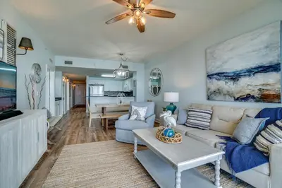 a living room with a couch and a ceiling fan at 408E Calypso Elegant beach front Beach Svc Included in Panama City Beach