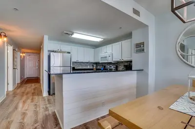 a kitchen with white cabinets and a white refrigerator at 408E Calypso Elegant beach front Beach Svc Included in Panama City Beach