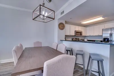 a kitchen and dining room with a wooden table and chairs at 1104 West 3 Bedrooms including 2 King Bedrooms and Custom Room in Panama City Beach
