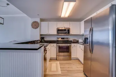 a kitchen with white cabinets and a stainless steel refrigerator at 1104 West 3 Bedrooms including 2 King Bedrooms and Custom Room in Panama City Beach