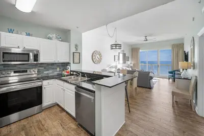 a kitchen with white cabinets and a view of the ocean at Calypso 2308 West Penthouse Views Totally Remodeled in Panama City Beach