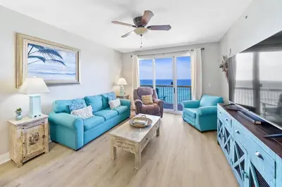 a living room with a blue couch and chairs at Calypso 1206 West Direct Gulf Front Custom Walk In Shower in Panama City Beach