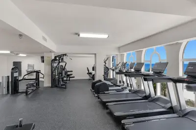 a gym with rows of treadmills and machines at Calypso 1206 West Direct Gulf Front Custom Walk In Shower in Panama City Beach