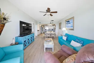 a living room with a blue couch and a table at Calypso 1206 West Direct Gulf Front Custom Walk In Shower in Panama City Beach