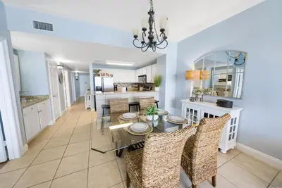 a dining room and kitchen with a glass table and chairs at 2206E Calypso Direct Gulffront Brand new remodel in Panama City Beach