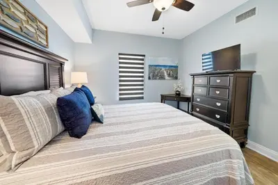 a bedroom with a large bed with a dresser and a television at 2206E Calypso Direct Gulffront Brand new remodel in Panama City Beach