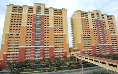 two tall buildings with palm trees in front of a street at Calypso 2201E 3BR 3BA corner unit 2 sets of beach chairs in Panama City Beach