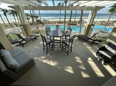 a patio with a table and chairs and the beach at Grand Panama 205 in Panama City Beach