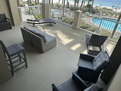 a room with a balcony with chairs and a pool at Grand Panama 205 in Panama City Beach