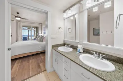 a bathroom with two sinks and a bedroom with a bed at Grand Panama 205 in Panama City Beach