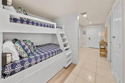 a white room with a bunk bed and a hallway at Grand Panama 205 in Panama City Beach