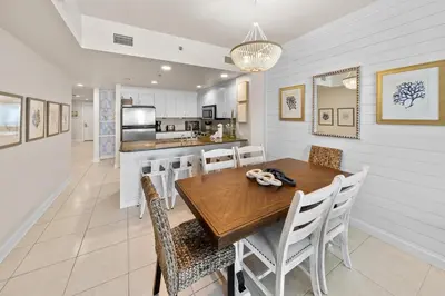a kitchen and dining room with a wooden table and chairs at Grand Panama 205 in Panama City Beach