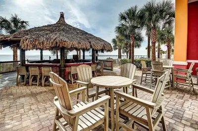 a patio with a table and chairs and a bar at Calypso 2006W Gulf Front and Newly renovated Custom Shower in Panama City Beach