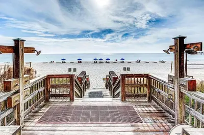 a wooden walkway leading to the beach with chairs and umbrellas at Calypso 2006W Gulf Front and Newly renovated Custom Shower in Panama City Beach