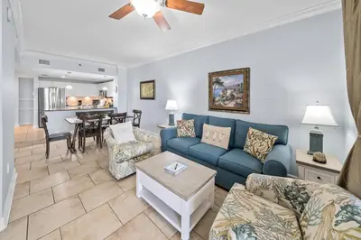 a living room with a blue couch and a table at Grand Panama 207 in Panama City Beach