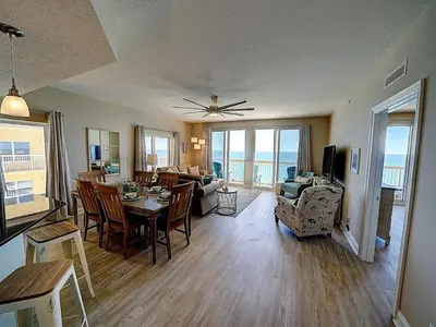 a living room with a dining table and a living room with the ocean at Calypso 1801W Corner Unit Incredible wrap around Balcony in Panama City Beach
