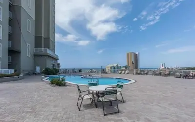a patio with a table and chairs next to a pool at Grand Panama 407 in Panama City Beach