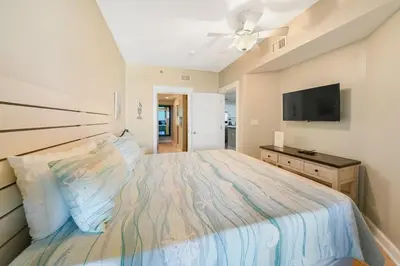 a bedroom with a large bed and a flat screen tv at Grand Panama 407 in Panama City Beach