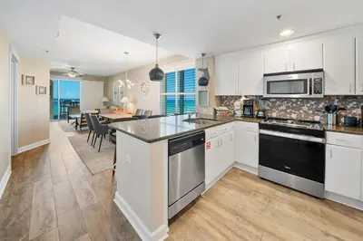 a kitchen with white cabinets and a dining room at Grand Panama 501 in Panama City Beach