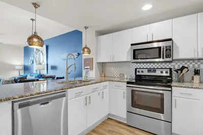 a kitchen with white cabinets and stainless steel appliances at Grand Panama 604 in Panama City Beach