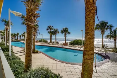 a swimming pool with palm trees and the beach at Calypso 1601W Gulf Front Corner unit Fantastic Specials in Panama City Beach