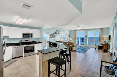 a kitchen with white cabinets and a table and chairs at Calypso 1601W Gulf Front Corner unit Fantastic Specials in Panama City Beach