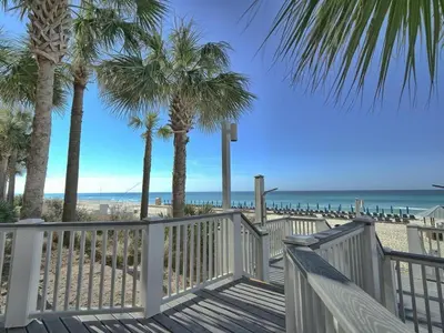 a wooden walkway to the beach with palm trees at Calypso 1401E 3BR 3BA Corner unit Direct Gulf Front High Demand in Panama City Beach