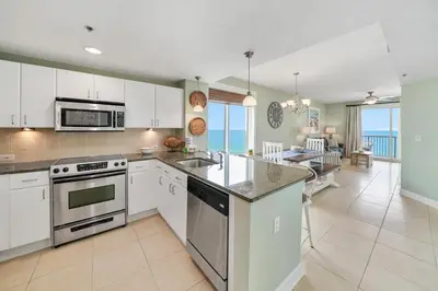a kitchen with white cabinets and a view of the ocean at Grand Panama 809 in Panama City Beach
